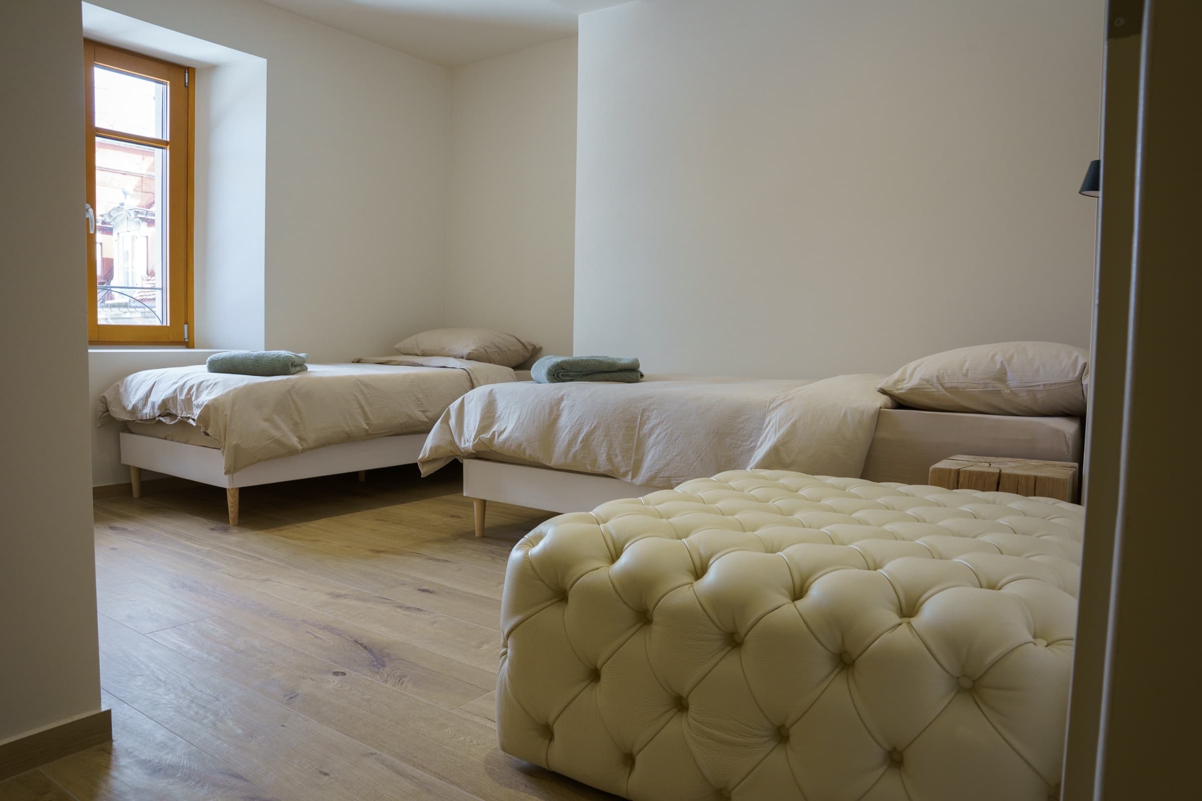 Suite Twin — deux lits simples en lin beige, banquette Chesterfield crème